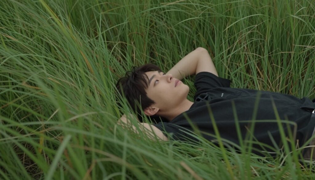 Osoba leżąca w wysokiej trawie symbolizująca refleksję nad oczekiwaniami w interpretacji snów